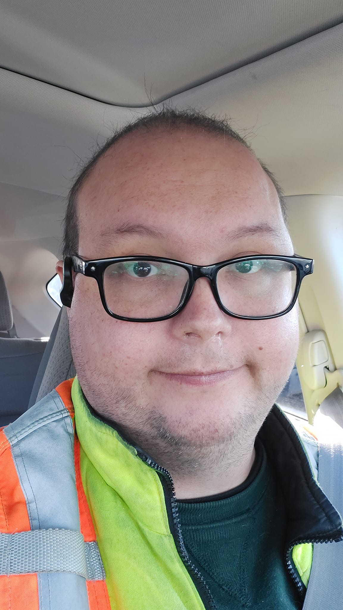 A man with sparse, short fuzzy hair sits in a car